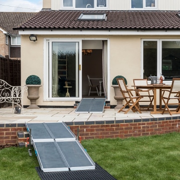 Back garden with Rollout-Trackway on lawn and NEW Aerolight-High Rise combination full-width ramp kit and NEW Aerolight-Xtra full-width suitcase ramp leading into patio doors of house